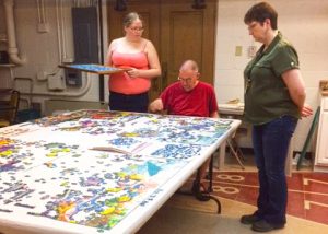 John Noer and family working on jigsaw puzzle.
