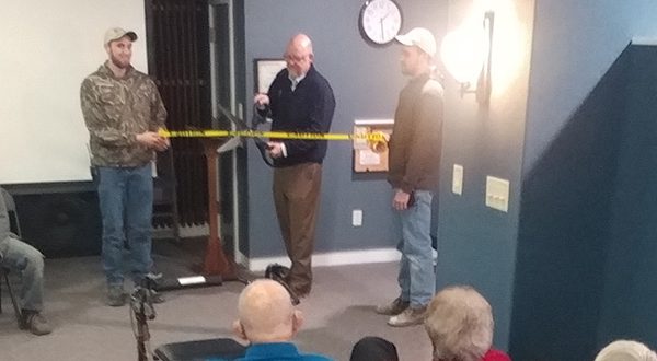 Steve Langerud, Mayflower Executive Director, cuts caution-tape “ribbon” held by craftsmen, Wyatt Crawford and Matt Spencer, and flanked by the rest of the Facilities staff.