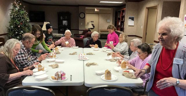 Beebe Assisted Living residents work on their gingerbread houses with Girl Scouts in the Activities Room