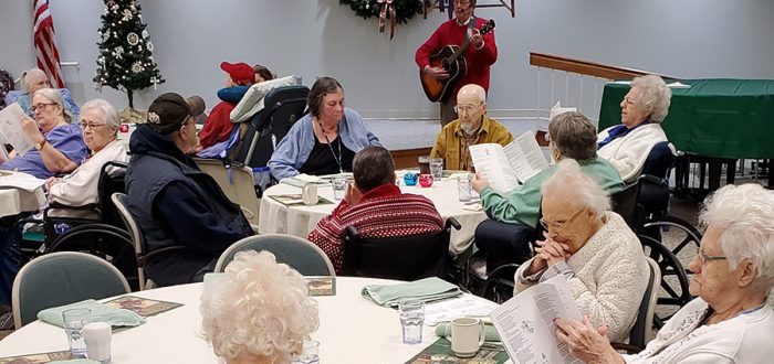Gene Wubbels entertains Health Center residents with Christmas carols in the Health Center. Gene is President-Elect of the Mayflower Residents Association.