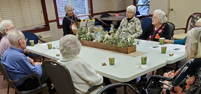 Jean Libbey (black sweater), Mayflower Book Club member, plays “Silent Night” on “Hugo,” the cello.
