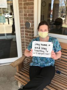 Casie Vande Stouwe, LPN holding sign saying "stay home and stay health, we'll see you soon!"