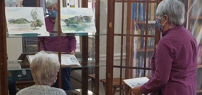 Karin Connelly and friend add paintings to Treasure Chest display in Pearson Building