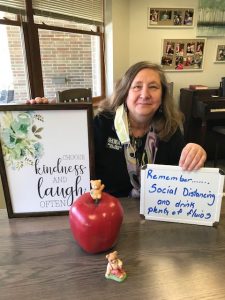 Rhonda Hudson, LBSW holding signs - "choose kindness and laugh often" and "remenber social distancing and drink plenty of fluids"