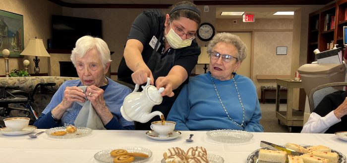Foodservice staff member Rosie Mumm pours tea for Pat Groth (left) and Deena Wellborn.